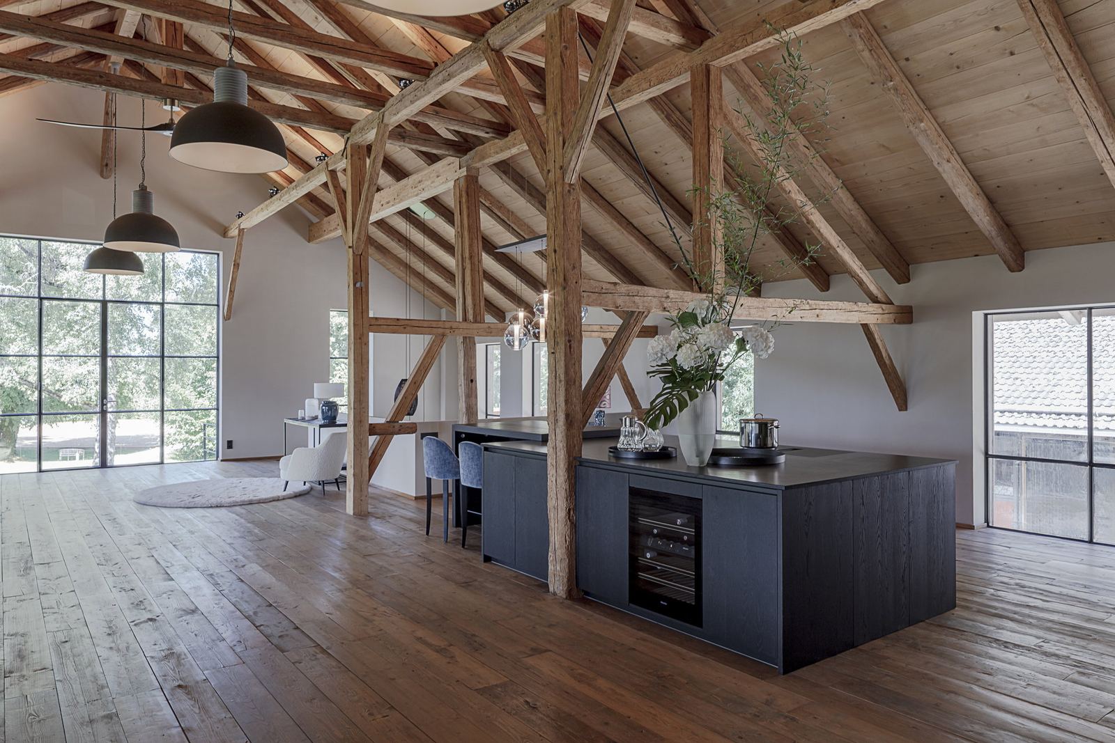 Loftküche mit Holzfronten und Insel vor altem Gebälk